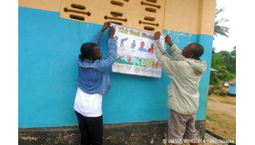 カイラフンで、エボラの症状や予防法が描かれたポスターを壁に貼るスタッフ