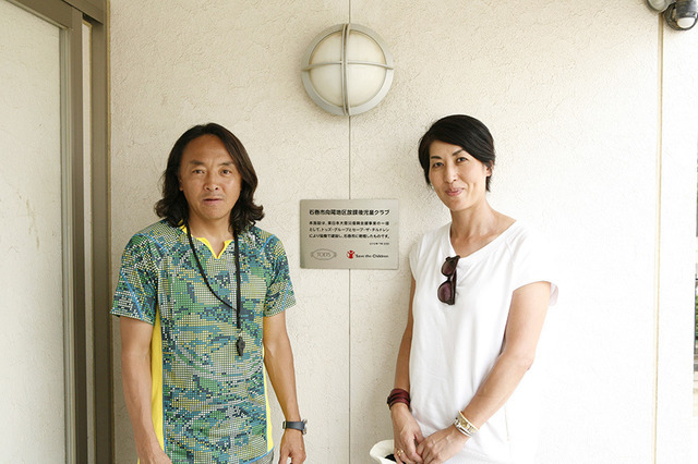 左から北澤豪氏、トッズ代表取締役・宅間頼子氏。トッズの寄付により設立された向陽小学校学童施設入り口にて。中央プレートにはトッズとセーブ・ザ・チルドレンのロゴが入っている