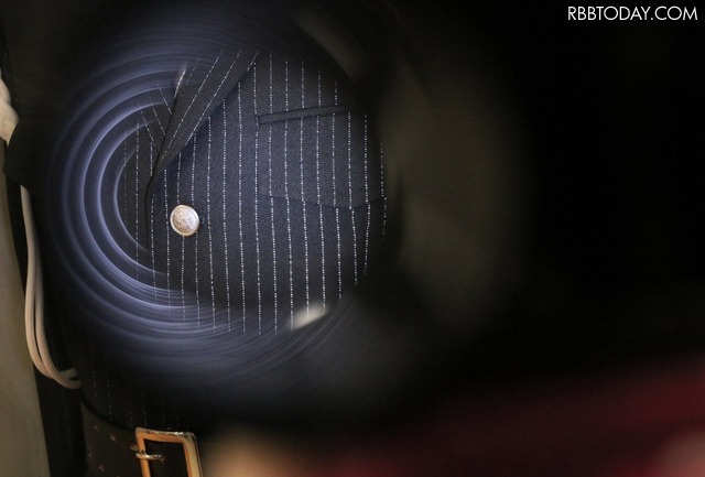 暗闇で「NIGHT PLUS」に光を当てると、再帰反射する糸がストライプ状に浮かび上がり、視認性を高める。夜間の交通整理や警備活動などで従来型のベストを着ることなく、制服のみで安全確保が図れるアイデア製品といえる（撮影：防犯システム取材班）