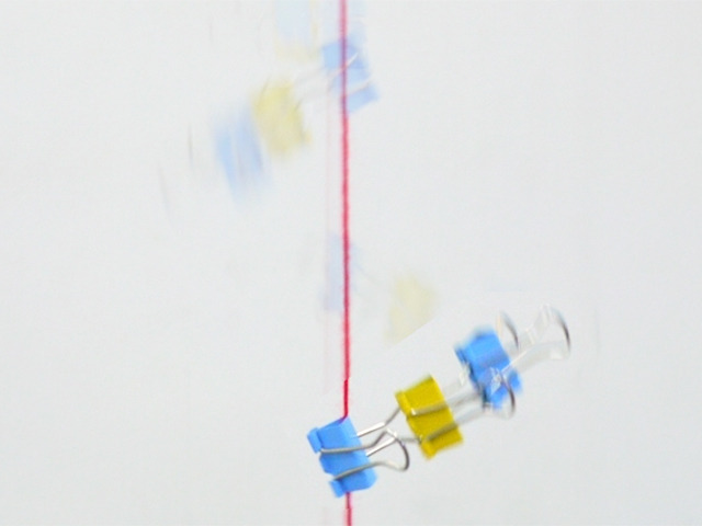 ２）端のクリップに毛糸（1.5mくらい）を通し、とびらなどを利用して、上から下まで毛糸を固定する。もしくは、保護者が毛糸を上下に伸ばして持つ。