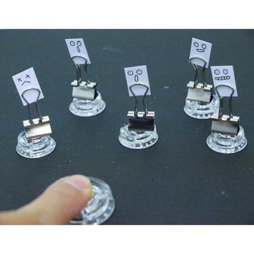 ３）顔を描いた紙をダブルクリップに挟み、磁石につけると、人が散らばるように逃げいていく。