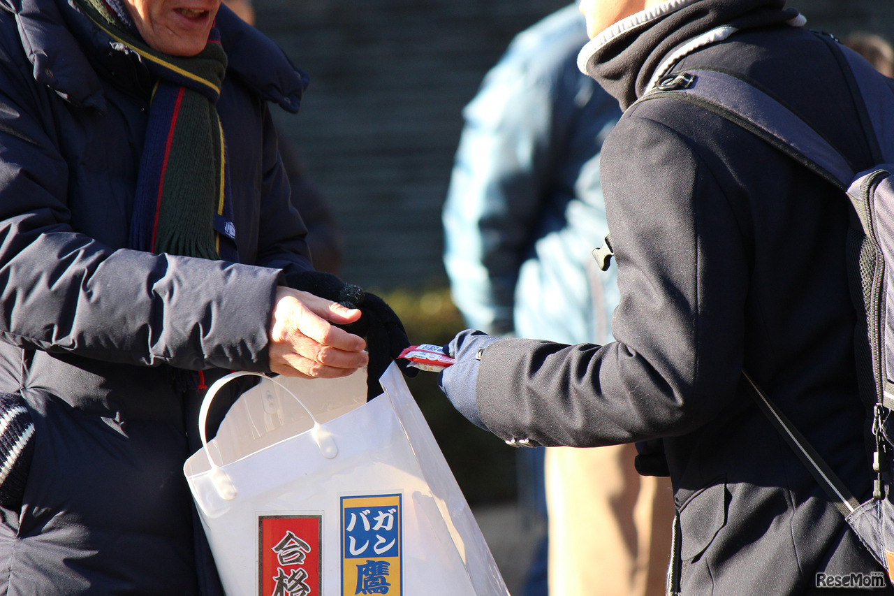 一橋大学国立キャンパス試験場では、受験生の応援にかけつけた関係者の姿が見られた。ゲン担ぎお菓子を手渡し、ひとりひとりに心からの応援を送る