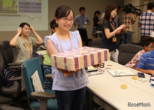 模擬券を使用した1億円パックの重さ体験（写真は過去開催時のようす）