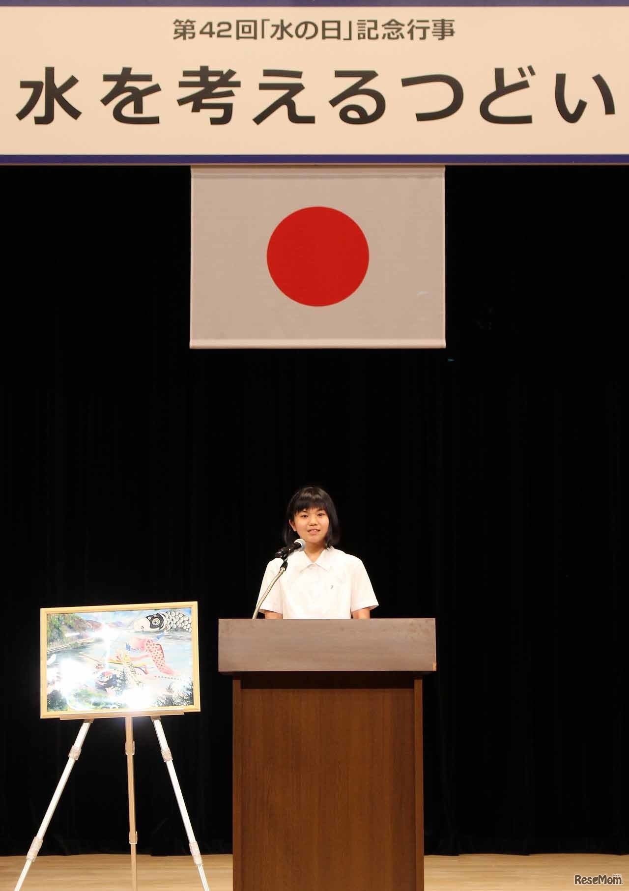 朗読中の井崎英里さん。横には、自身が描いた絵が飾られている