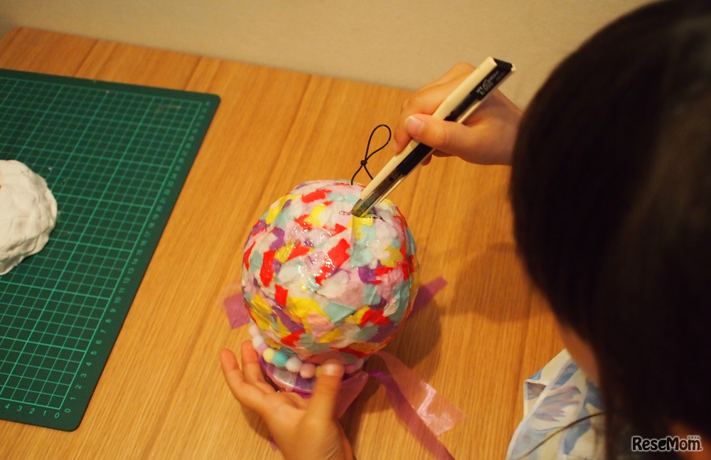 怖いと言いながら貯金箱の穴をカッターで切り取る。うまく刃が入らないところはサポート