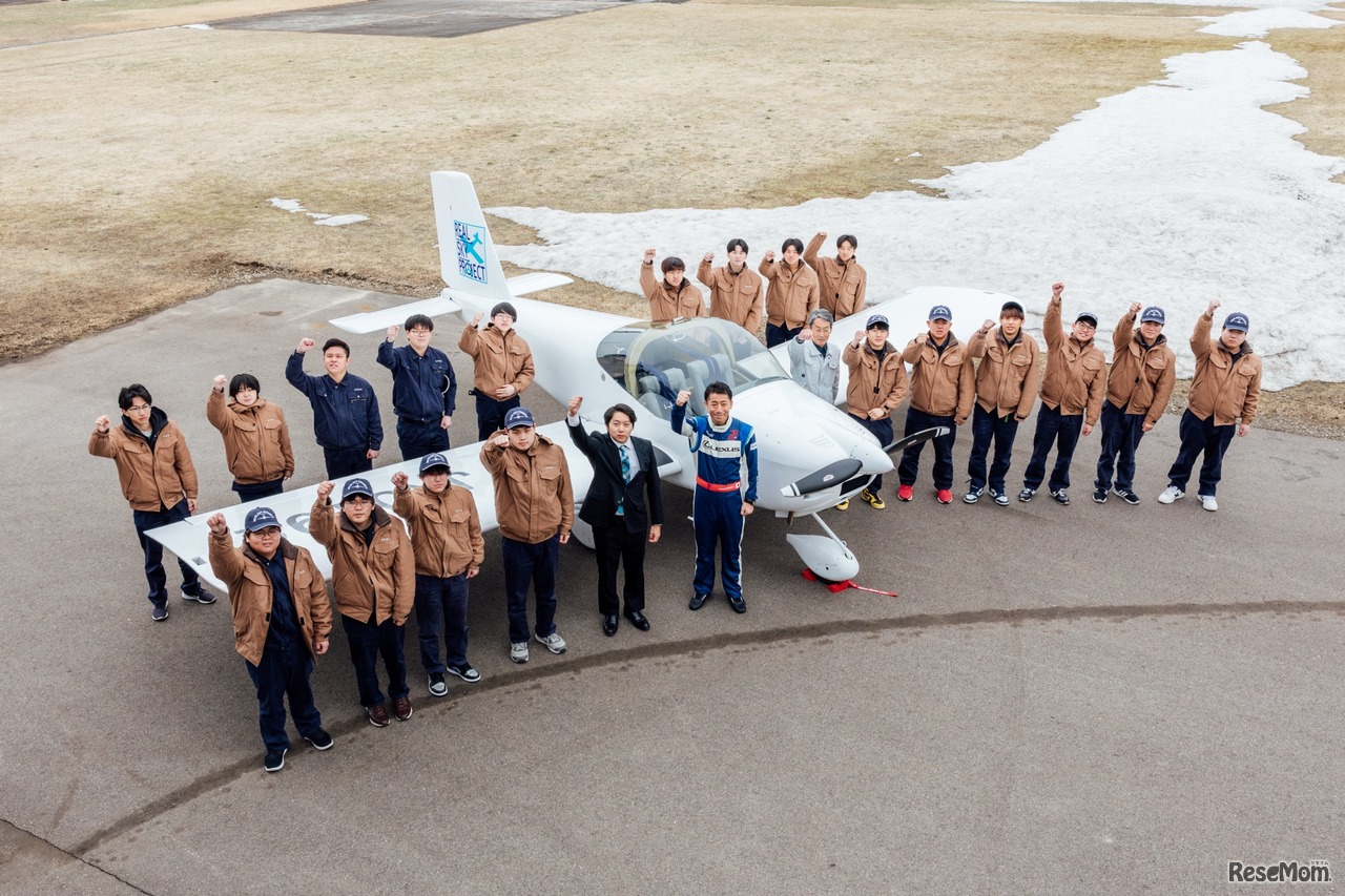 軽量飛行機を囲んで記念撮影するテクノアカデミーの学生と室屋義秀選手