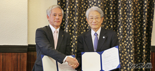 協定書署名の後、握手を交わす松本総長（右）と山口教育長（左）