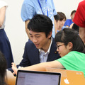 iPhoneアプリの制作体験に挑戦する小泉進次郎氏。参加生徒を「先輩」と仰ぎ、プログラミングについて解説してもらう場面も