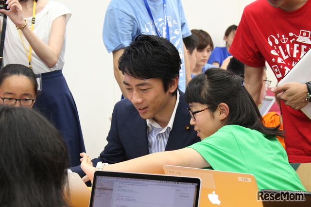 iPhoneアプリの制作体験に挑戦する小泉進次郎氏。参加生徒を「先輩」と仰ぎ、プログラミングについて解説してもらう場面も