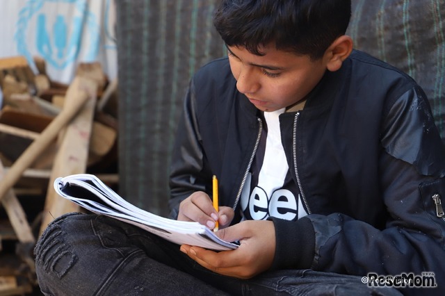 ノートを見返すシリア難民の男の子（レバノンの難民キャンプ）