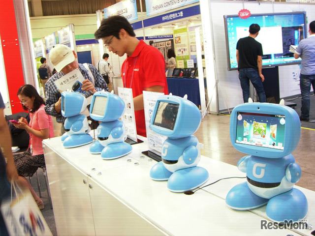 韓国最大手キャリアのKTが展示したKibotという幼児・小学生向け教育ロボット。子供とロボットが一緒に英語で歌って踊るコンテンツを提供しており、親が選んでダウンロードする。防犯カメラ、ボタン一つで保護者の携帯電話にテレビ電話をかける機能もある